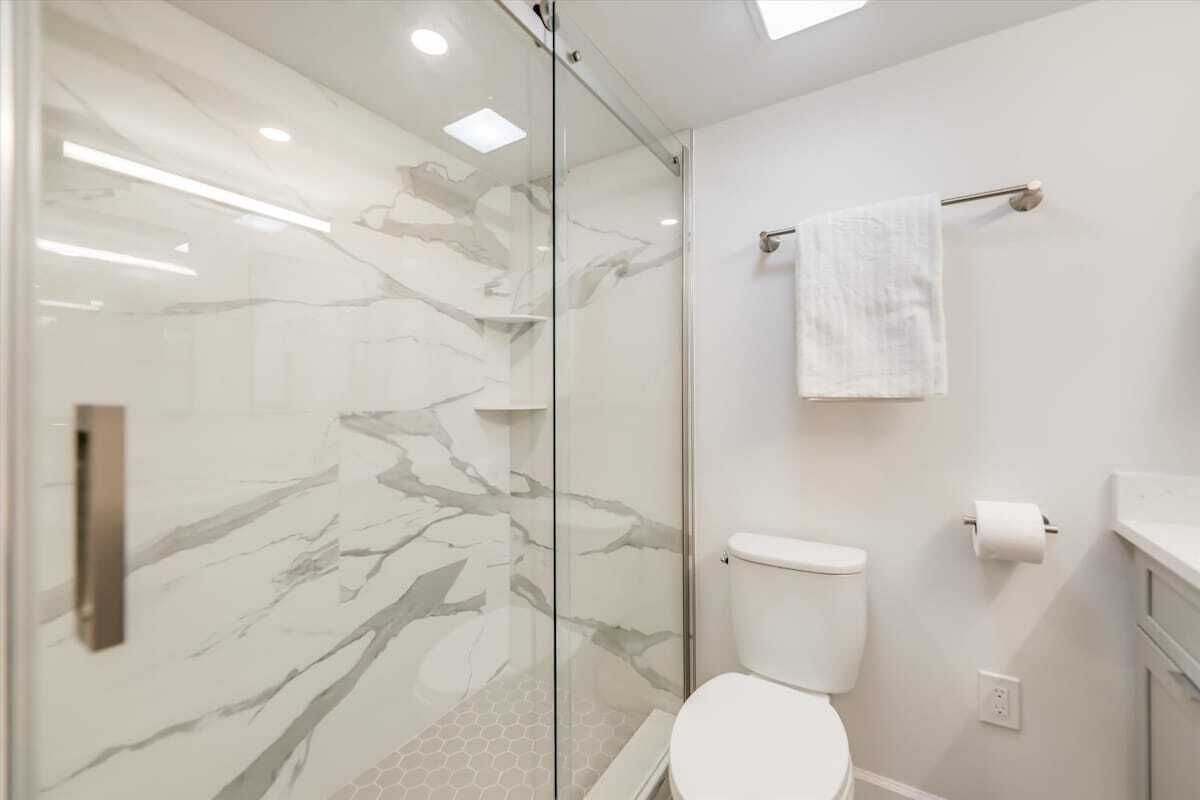 Un baño moderno con cabina de ducha de vidrio, inodoro y toallero.