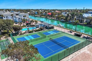 A tennis court with a pool, surrounded by buildings and a river. - Sanibel Waterfront 3BR | Dock, Pool, Pickleball (Sanibel)