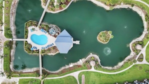 Un resort con piscina central, un puente y una pequeña isla.