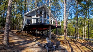Eine Hütte mit einer Terrasse, Sitzgelegenheiten im Freien und einer amerikanischen Flagge.