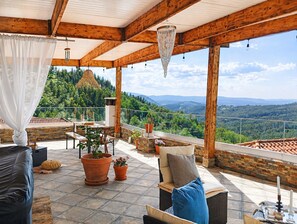 Un espace extérieur abrité, aménagé avec des sièges, et offrant une vue sur un paysage montagneux.