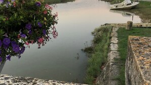 Un'acqua calma con una barca, un muro in pietra e un aiuola di fiori.