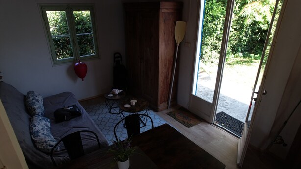 Una stanza con un letto, un tavolo con una pianta, una finestra con un palloncino rosso e una porta che dà sull'esterno.