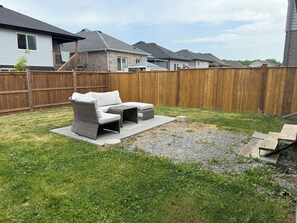 Un patio trasero con un conjunto de muebles, cerca de madera y casas al fondo.