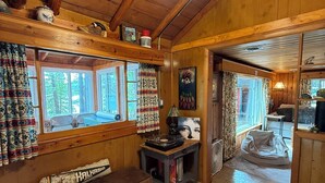 Ein gemütliches Blockhaus-Interieur mit Holzwänden, einer Bank, einem Tisch mit Lampe und einem Deckenventilator.