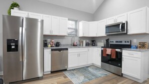 A modern kitchen with white cabinets, stainless steel appliances, and a wooden floor. - Luxe Downtown Townhome-Sleeps 6 Brand New Build! (Indianapolis)