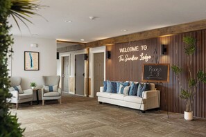 A reception area with a sofa, chairs, a welcome sign, a chalkboard sign, and a wooden wall. - The Sandbar Lodge at Torch Lake (Rapid City)