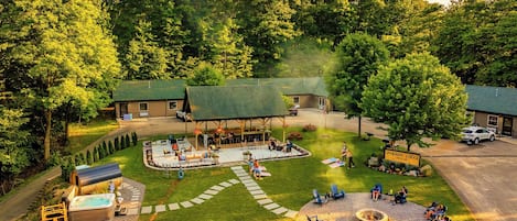 A lodge with a covered patio, outdoor seating, a hot tub, and a fire pit area.