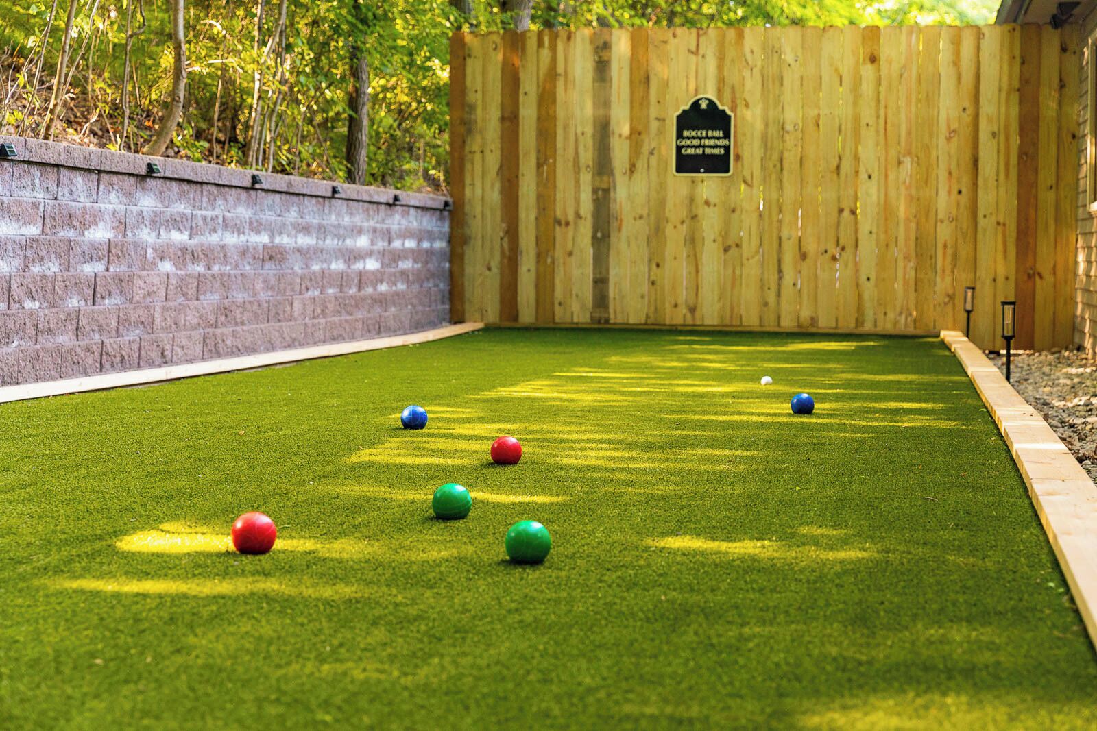 Una cancha de bochá con valla de madera y pared de ladrillo.