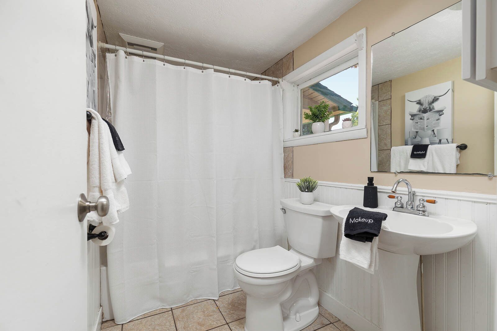 Une salle de bain avec des toilettes, un lavabo et un rideau de douche.
