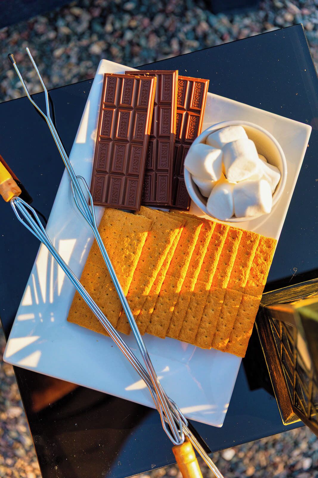 A dessert tray with chocolate bars, marshmallows, and cookies.