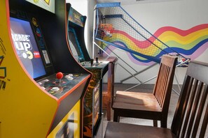 Een kamer met een spelconsole, een stoel en een kleurrijk speelgedeelte.
