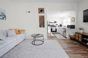 Een moderne woonkamer met een bank, salontafel en een keuken op de achtergrond.