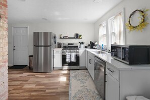 Een moderne keuken met roestvrijstalen apparatuur, een wit aanrecht en een houten vloer.
