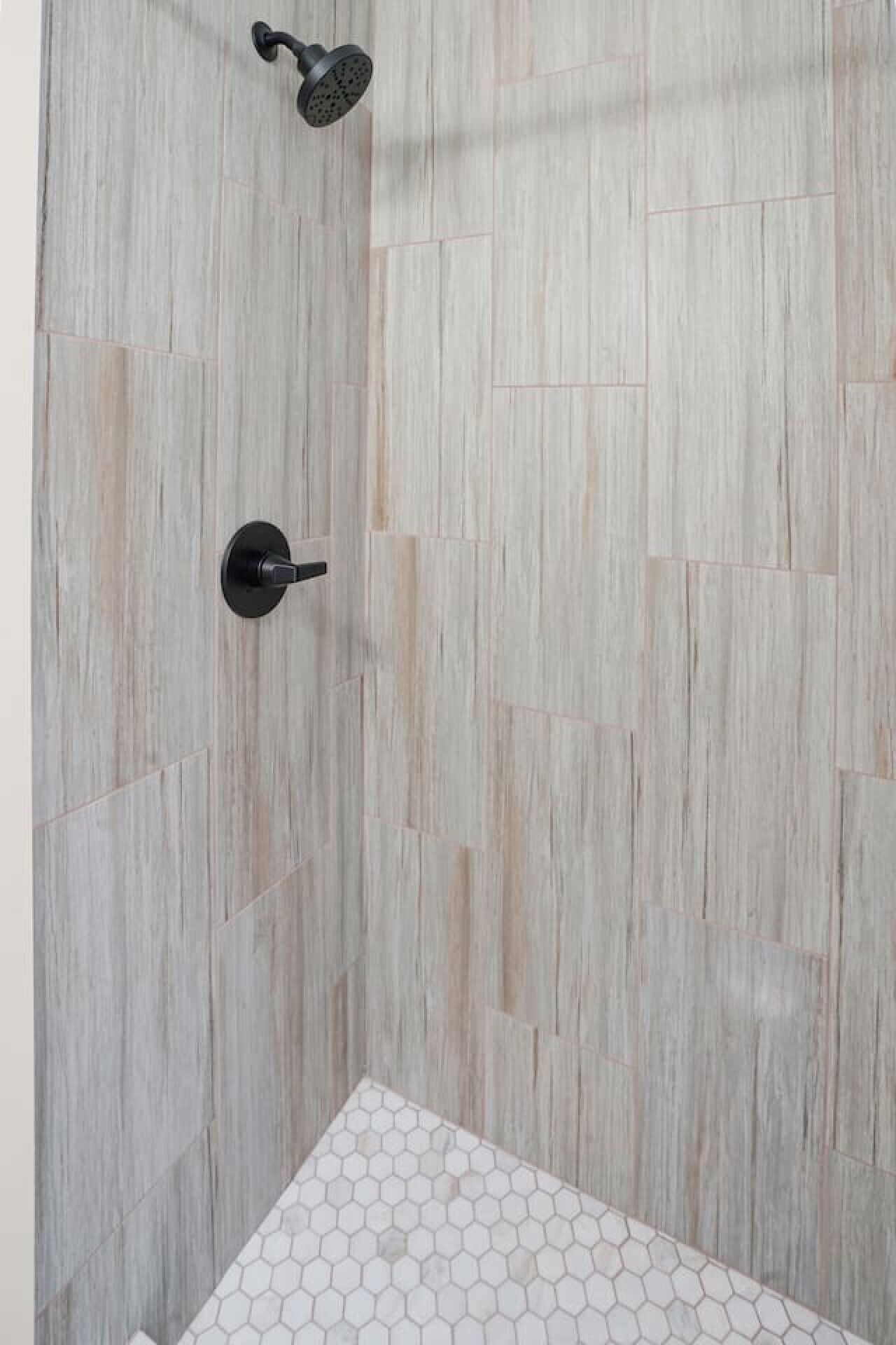 Een douche met een houten wand en een mozaïek van zeshoektegels onderin.