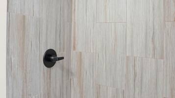 Een douche met een houten wand en een mozaïek van zeshoektegels onderin.