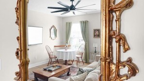 A room with a large ornate mirror, a ceiling fan, a dining table with chairs, and a sofa. - Chic Downtown Franklin Condo-Sleeps 6! (Franklin)