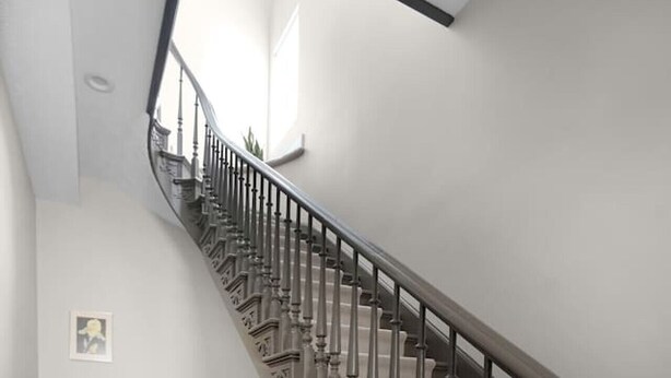 A staircase with a dark balustrade, a wooden chair, a desk with a lamp, and a patterned rug. - Chic Downtown Franklin Condo-Sleeps 6! (Franklin)