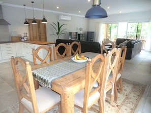 A dining area with a wooden table, chairs, and a bowl of fruit.