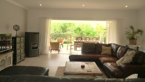 A living room with a leather sofa, a wooden coffee table, a TV, and a fireplace. - Beautiful villa near Meia Praia, Lagos with solar heated pool & lots of space (Lagos)