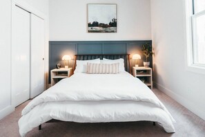 A neatly made bed with white bedding, two bedside tables with lamps, a headboard, and a framed picture on the wall. - Cute Fountain Square Cottage-sleeps 4 (Indianapolis)