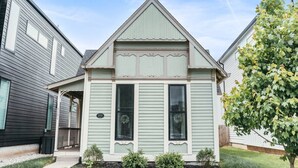 Een twee verdiepingen tellend huis met een puntige gevel, een veranda en een kleine voortuin.