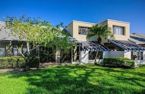A modern residential building with a flat roof, large windows, and a well-maintained lawn. - Spacious 3-bedroom condo with a golf course view (Sarasota)