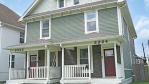 Ein zweigeschossiges Haus mit Veranda, Garage und einem gepflegten Rasen.
