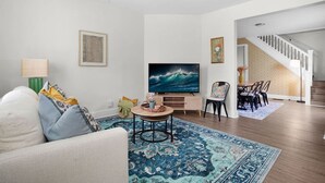 Ein Wohnzimmer mit einer Couch, einem Fernseher und einem Essbereich mit Stühlen.
