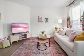 Un salon comprenant un téléviseur, un canapé, une table basse et des coussins décoratifs.