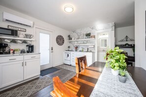 Eine moderne Küche mit weißen Schränken, einer Marmorarbeitsplatte und einem Essbereich mit Holztisch und Stühlen.