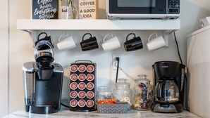 En köksbänk med en kaffebryggare, en Keurig-maskin, ett fack för kaffekapslar, burkar och en mikrovågsugn.