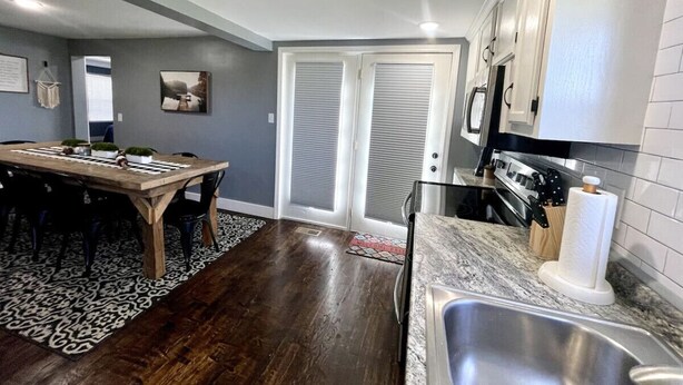 A kitchen with a marble countertop, a stainless steel sink, and a dining area with a wooden table and chairs. - Wolf River Getaway-close to dock (Highway)