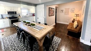 A modern kitchen with white cabinets, a wooden dining table, and a brown sofa in a living area. - Wolf River Getaway-close to dock (Highway)