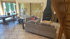 Una sala de estar con sofá, mesa de centro, chimenea, cinta de correr y mesa de comedor.