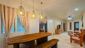 Ein geräumiger Essbereich mit einem langen Holztisch, Bänken und hängenden Korbtreleuchtern.