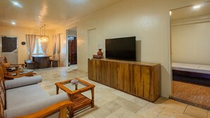 Ein Wohnzimmer mit Fernseher, Holzmöbeln und Deckenventilator.