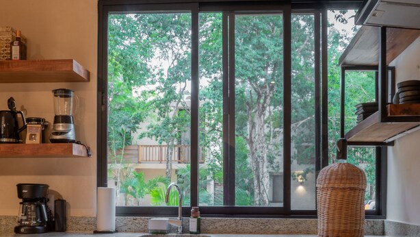 Eine Küche mit großem Fenster, Holzschränken und einer Edelstahl-Dunstabzugshaube.