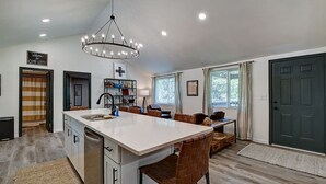 Una cocina moderna con una isla central, un comedor con sofá y un amplio ventanal.