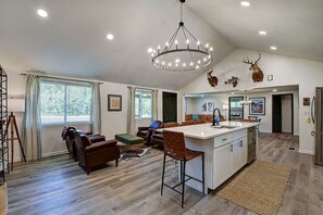 A spacious living area with a large island, a chandelier, and deer antlers on the wall. - Camp Collins-French Lick Gem! (French Lick)