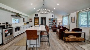 Una cocina moderna con una isla central, electrodomésticos de acero inoxidable y un comedor con mesa de madera y sillas de cuero.