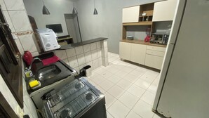 A kitchen with a gas stove, a sink, a refrigerator, and a microwave. - Beach house / Suarão - Itanhaém, 7 minutes walk from the beach. (Itanhaém)