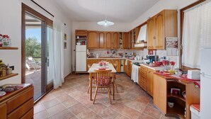 Una cocina con armarios de madera, una mesa de comedor con sillas y un ventanal corredero que da a un espacio exterior.