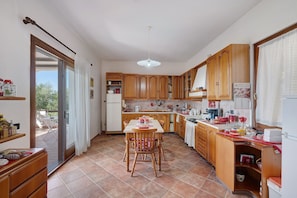 A kitchen with wooden cabinets, a dining table with chairs, and a sliding glass door leading to an outdoor area.
