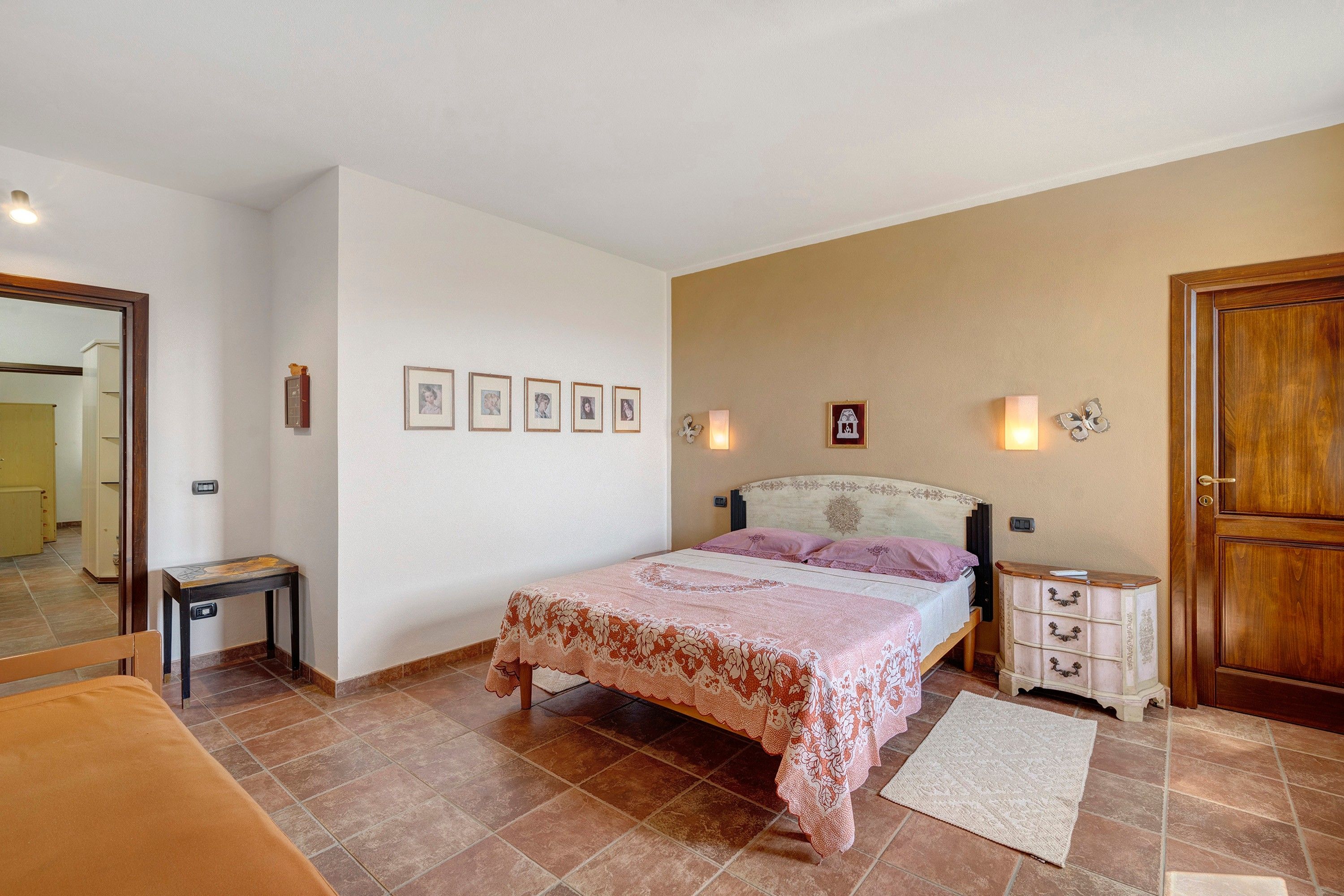Une chambre à coucher comprenant un lit, des tables de chevet, une commode, un miroir et des tableaux encadrés accrochés au mur.