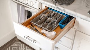 Un tiroir de cuisine contenant des ustensiles et un panier bleu.
