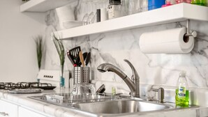 Une cuisine dotée d’un évier en acier inoxydable, d’une cuisinière à gaz et d’un dosseret en marbre.