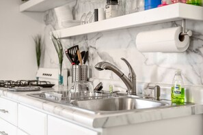 A kitchen with a stainless steel sink, a gas stove, and a marble backsplash. - Entire unit-Close to Lucas Oil! (Indianapolis)