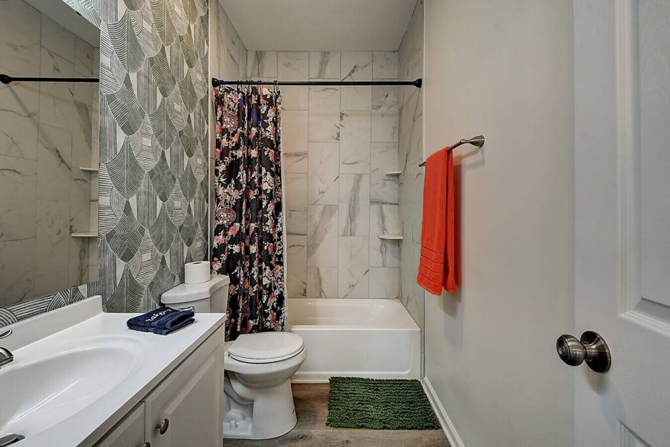 A bathroom with a toilet, shower, and sink.
