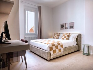 A bedroom with a bed, a desk, a chair, a radiator, a window with curtains, and a small table. - Casa Accademia in the Heart of Bologna (Bologna)